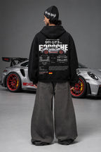 Full back view of the Porsche 911 GT3 RS hoodie beside a Porsche car