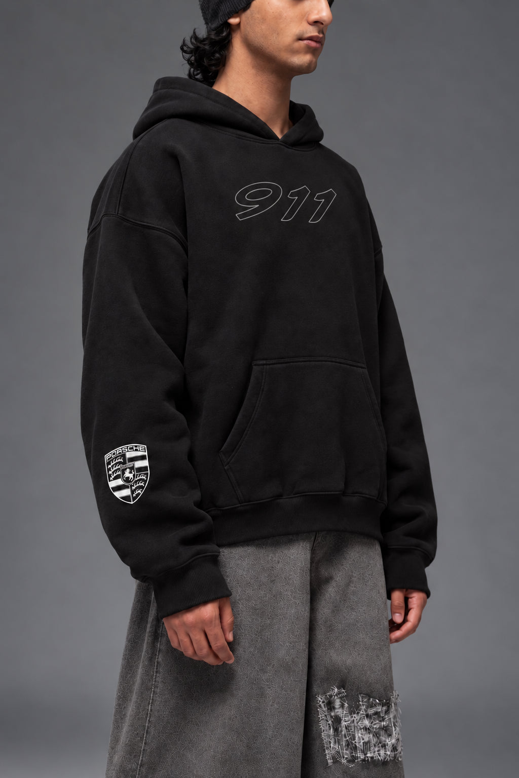 Three-quarter front view of the black Porsche 911 oversized hoodie