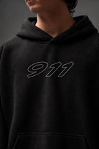 Close-up of the outlined 911 chest graphic on the black hoodie