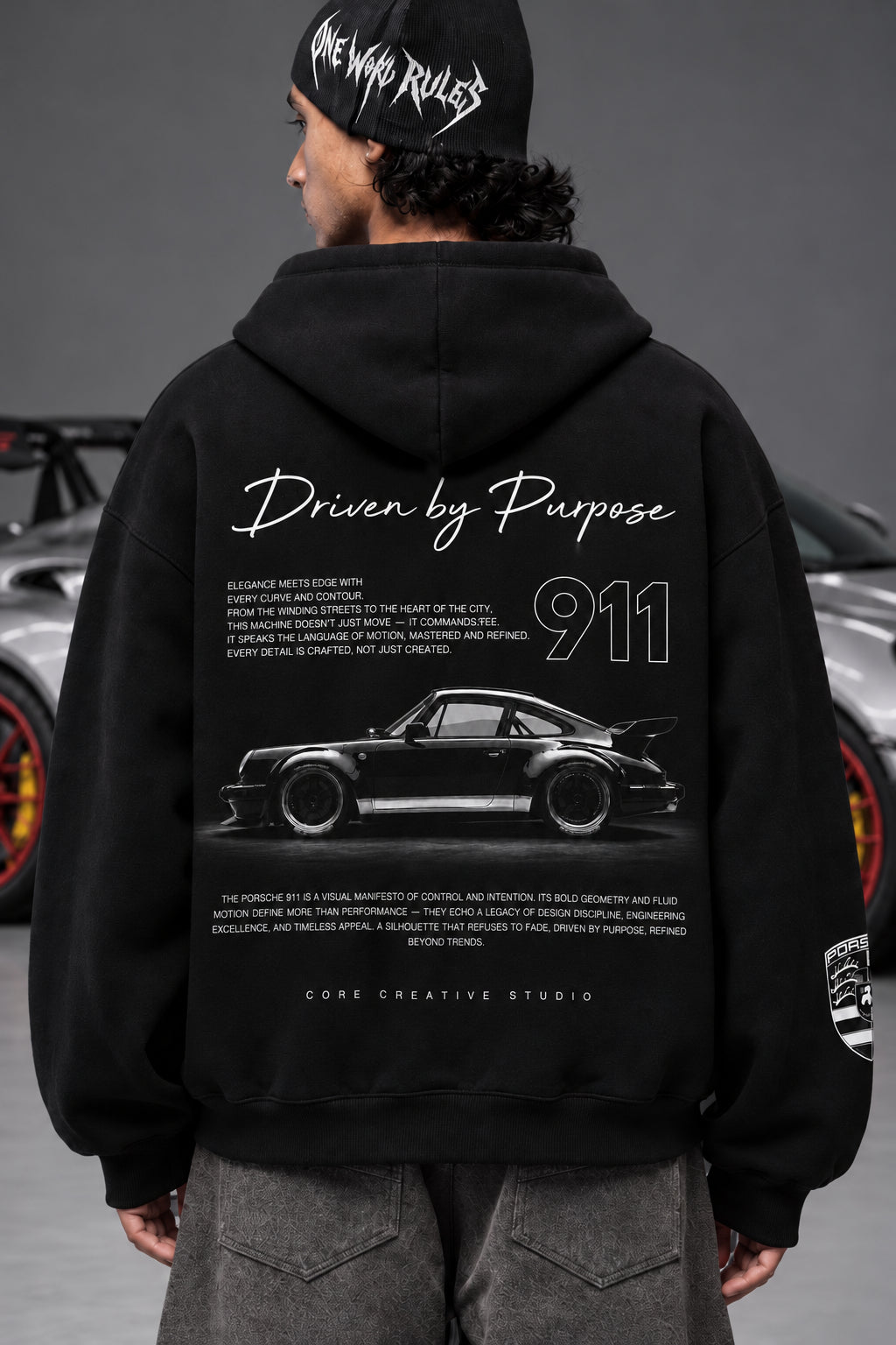 Rear view of the Porsche 911 hoodie showing Driven by Purpose artwork beside a Porsche car